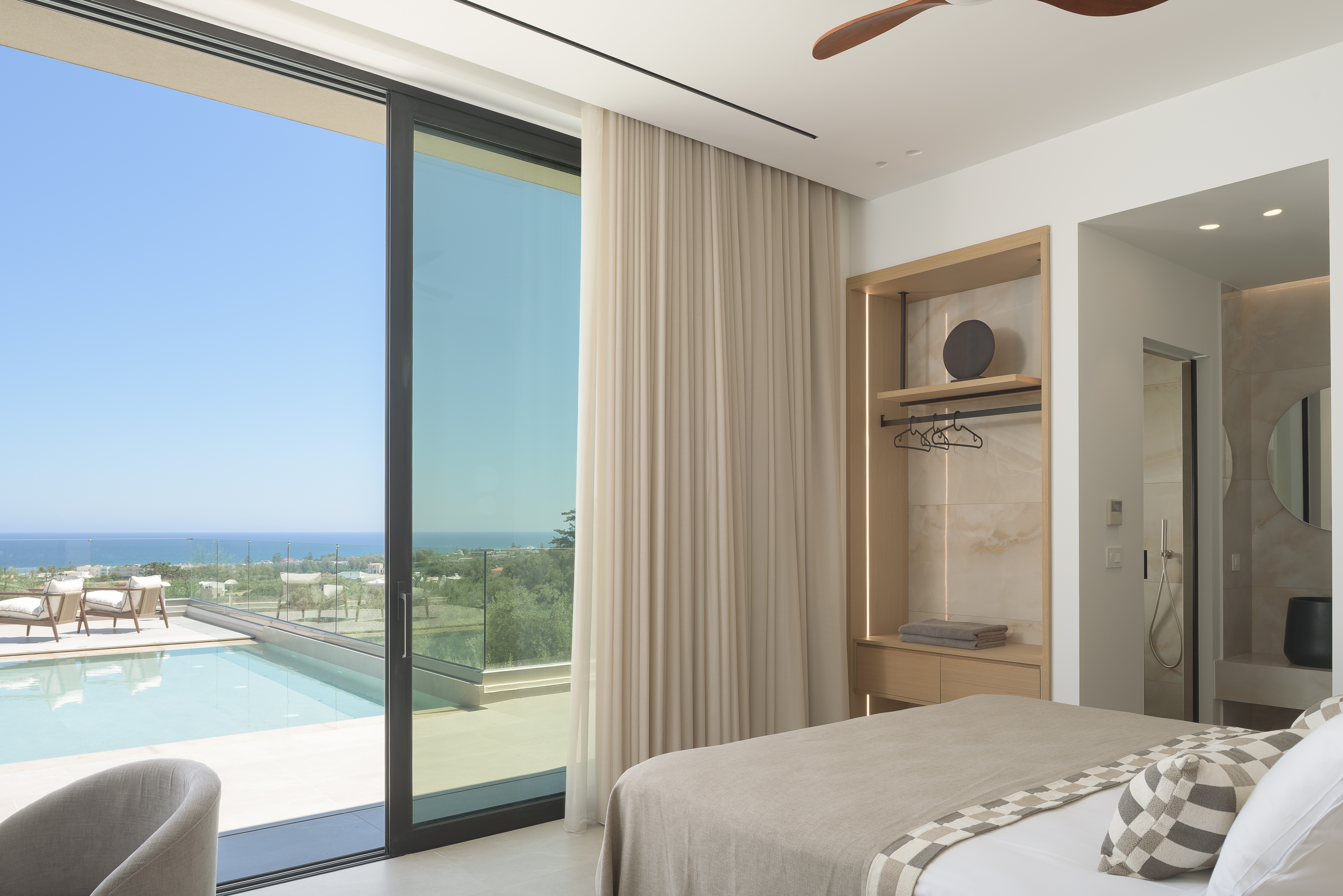 A serene en-suite double bedroom with direct access to the pool & sea-views, featuring an en-suite bathroom with walk in shower.