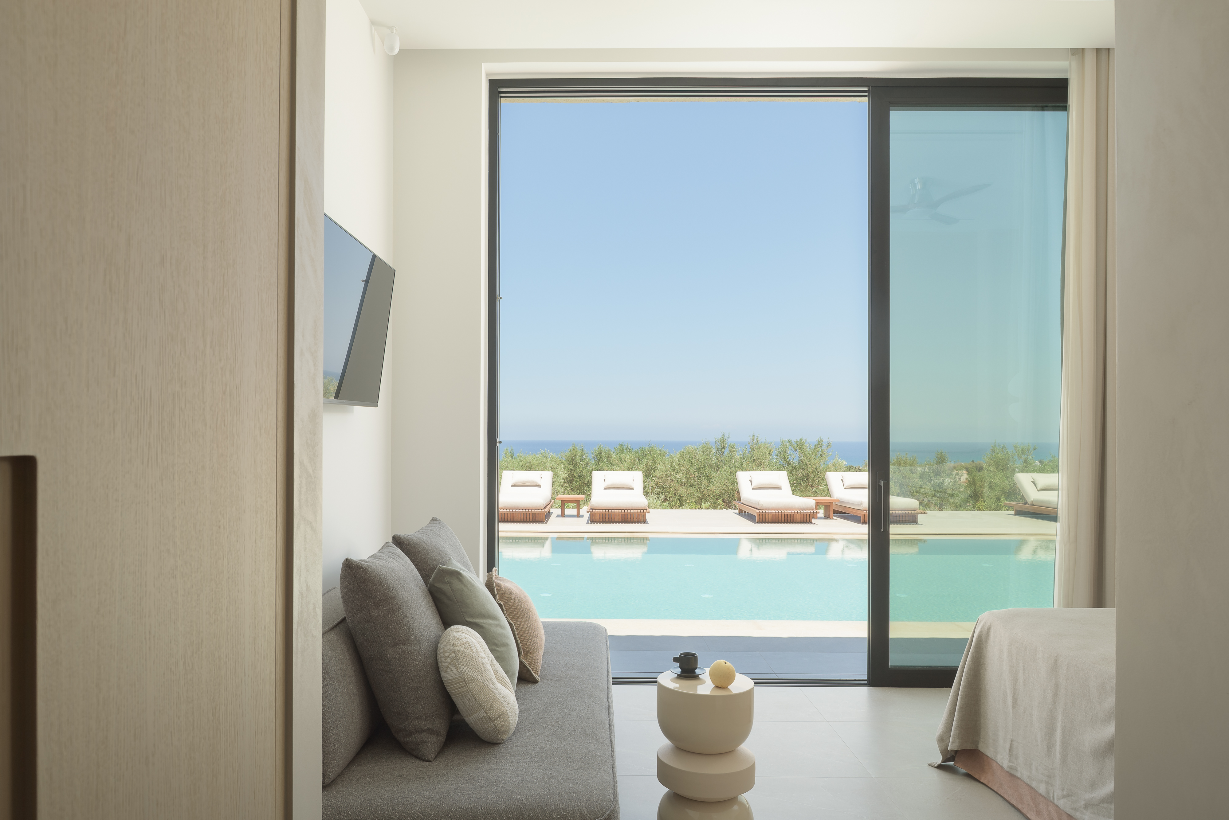 A beautifully composed bedroom with direct access to the pool, and an additional sofa bed for one more guest to sleep.